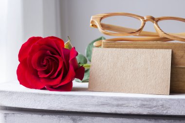 Kırmızı gül ve boş kahverengi kağıt antika kabine üzerinde