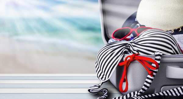 Bikini and clothes in luggage on wooden