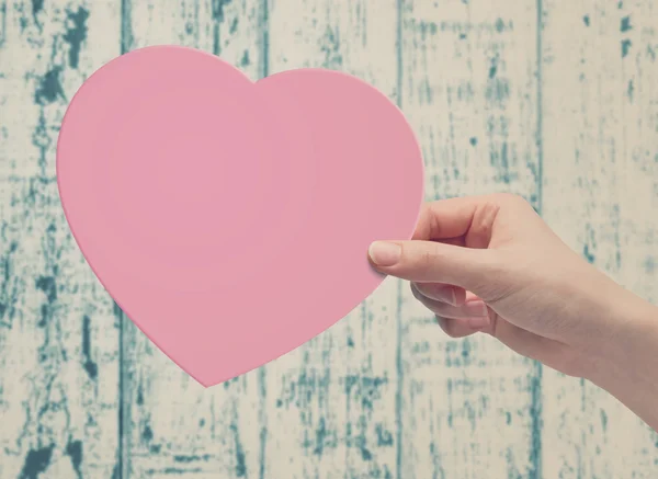 Mano recogiendo corazón de papel rosa — Foto de Stock