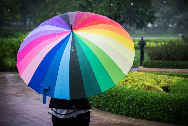 Jonge vrouw met multicolor paraplu in regenachtige dag — Stockfoto