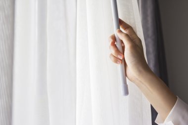 Genç kadın yatak odasında perdeleri açmayı