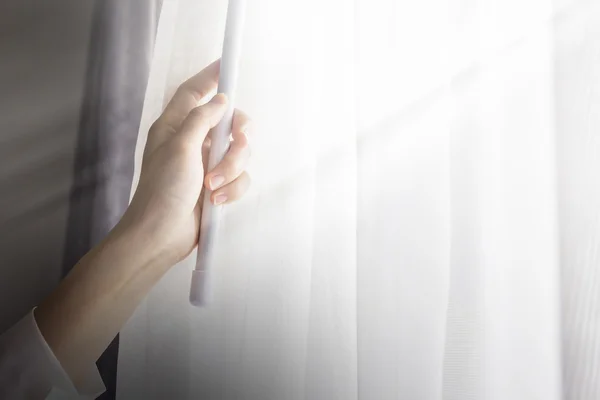 Ung kvinna öppna gardiner i sovrummet — Stockfoto
