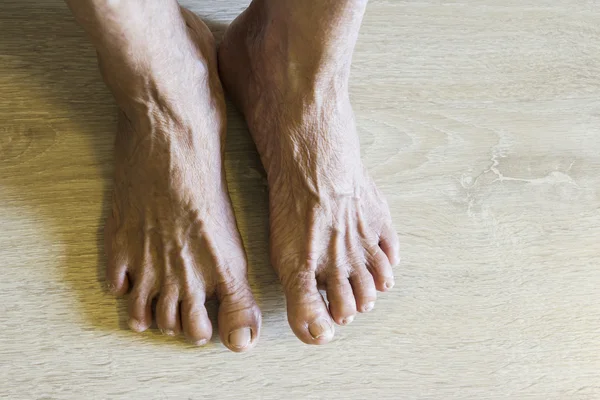 Old feet on wooden floor — Stock Photo, Image