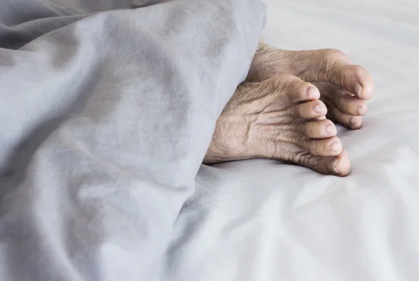 Old feet on the bed — Stock Photo, Image