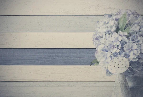 Vintage hydrangea flowers in zinc watering can on wooden backgro