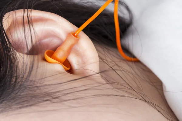 Young woman with earplugs sleeping on the bed — Stock Photo, Image