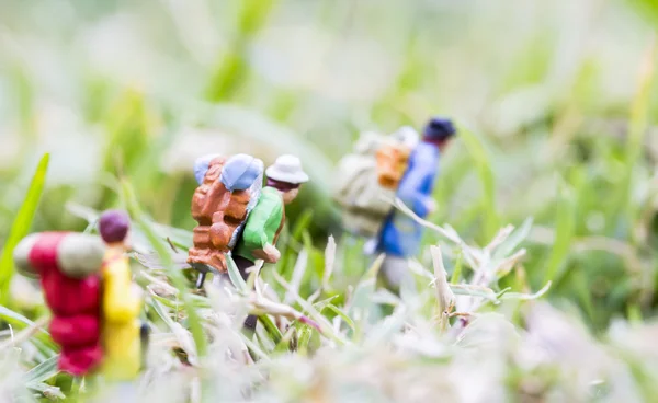 Mochileiros em miniatura andando na grama — Fotografia de Stock