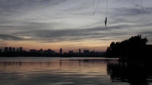 Solnedgång över sjön med stadens byggnader — Stockvideo