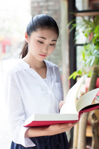 Mooie jonge vrouw met een boek in cafe — Stockfoto