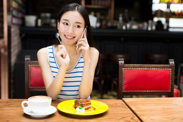 Όμορφη νεαρή γυναίκα που κάθεται και τρώει τούρτα — Φωτογραφία Αρχείου