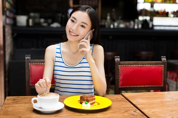 Schöne junge Frau sitzt und Kuchen isst — Stockfoto