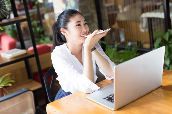 カフェで笑顔の若い女性が座っています。 ストックフォト