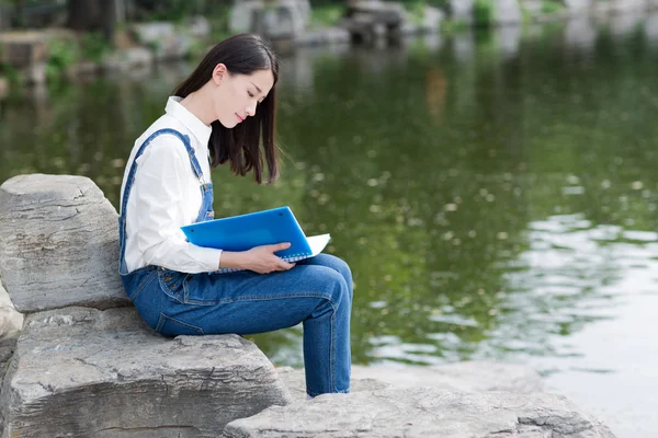 Menina sentada no lago ler — Fotografia de Stock
