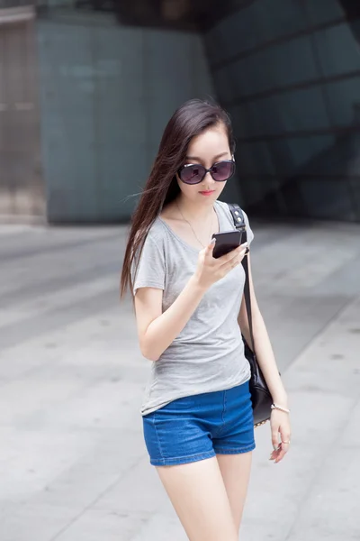 Mulher de compras usando óculos está enviando mensagens no centro — Fotografia de Stock
