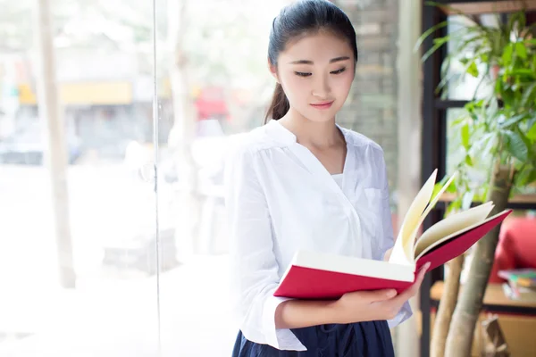Mooie jonge vrouw met een boek in cafe — Stockfoto