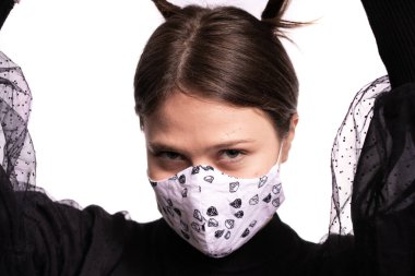 Maskeyle poz veren güzel bir genç kadın, beyaz arka planda siyah bir stüdyo resmi var.