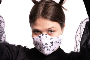 Maskeyle poz veren güzel bir genç kadın, beyaz arka planda siyah bir stüdyo resmi var.