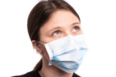 Maskeyle poz veren güzel bir genç kadın, beyaz arka planda siyah bir stüdyo resmi var.