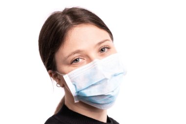 Maskeyle poz veren güzel bir genç kadın, beyaz arka planda siyah bir stüdyo resmi var.