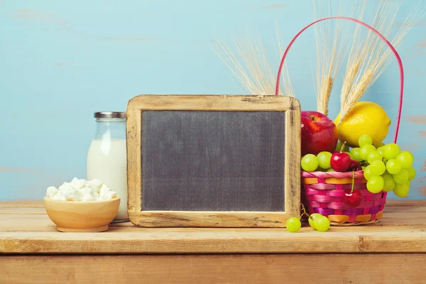 Chalkboard, milk and fruits basket — Stock Photo, Image