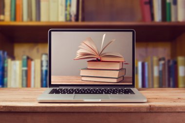 Dizüstü bilgisayar ve kitap yığını
