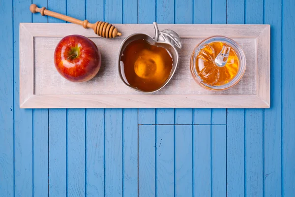 Мед и яблоко на деревянном синем столе — стоковое фото