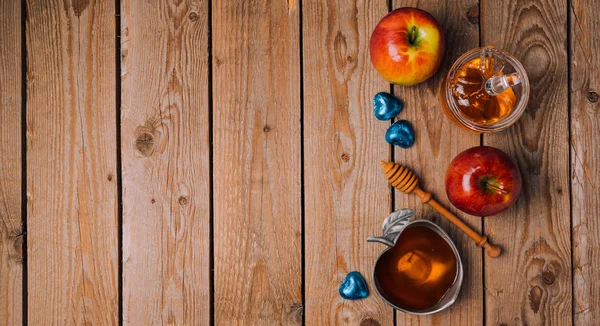 Miód, jabłka i czekolady na drewnianym stole — Zdjęcie stockowe