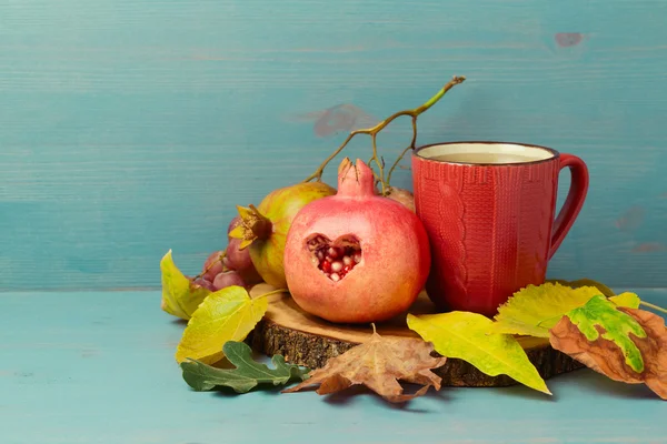 Tea cup, pomegranate and leaves — Stock Photo, Image