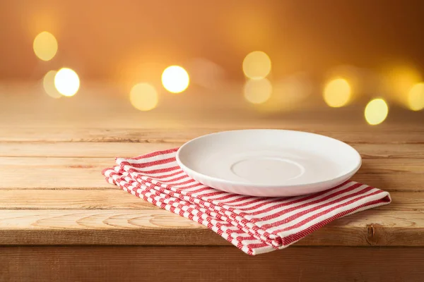 节庆灯亮背景下木制桌子上铺着带条纹桌布的空盘子 — 图库照片