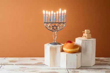 Yahudi bayramı Hanuka yaratıcı kavramı. Menorah ve geleneksel çörekler tahta masada podyumda.