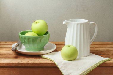 Ahşap masada yeşil elmalar ve mutfak malzemeleri.