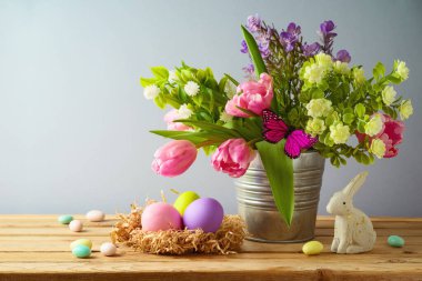 Paskalya tatili konsepti. Paskalya yumurtaları ve ahşap masada güzel lale çiçekleri.