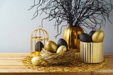 Paskalya bayramı konsepti, paskalya yumurtaları, siyah ve altın renkli ahşap masa.