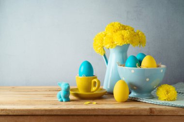 Paskalya bayramı konsepti Paskalya yumurtaları, çiçekler ve ahşap masa üzerindeki tavşan süslemeleri.