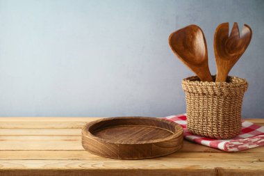 Masada boş ahşap tabaklar ve mutfak aletleri var. Ürün gösterimi için mutfak arka planı