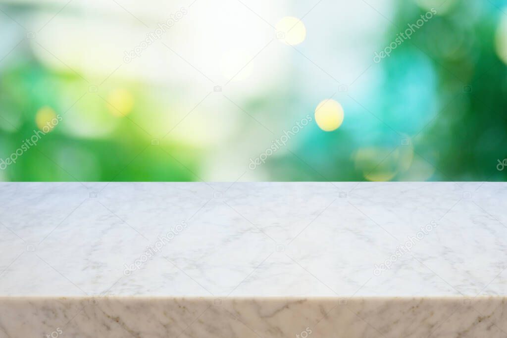 Empty marble table over green blurred background.  Summer mock up for design and product display. Selective focus on marble tabletop.