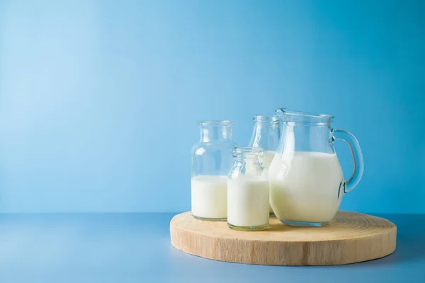 Milk bottles and milk jug over blue background. Modern still life composition. Healthy eating concept