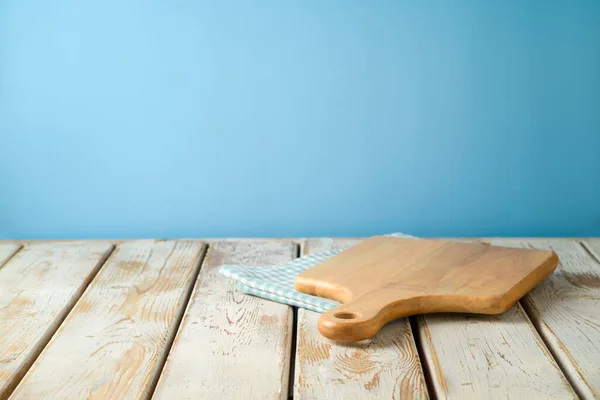 青い壁の背景にテーブルクロスとまな板と空の木製のテーブル デザインや製品表示のためのキッチンモックアップ — ストック写真
