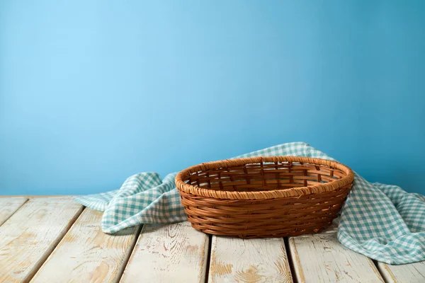 青い壁の背景に素朴な木製のテーブルの上にテーブルクロスと空のバスケット デザインや製品表示のためのキッチンモックアップ — ストック写真