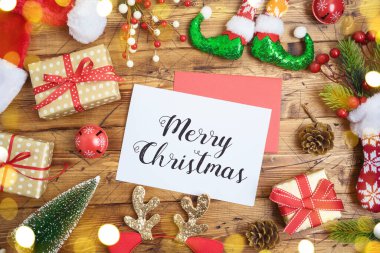 Mutlu Noel tebrik kartı hediye kutuları, Noel Baba şapkası ve ahşap arka planda süslemeler.