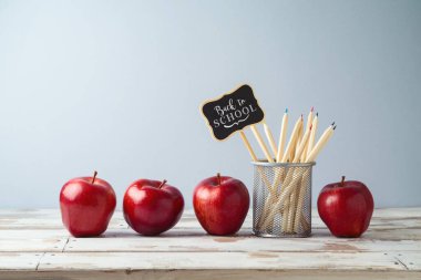 Kalemler ve elmalarla ahşap masada okul konseptine geri dönelim..