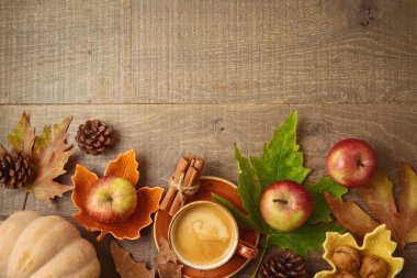 Kahve fincanı, elma, balkabağı ve sonbahar yaprakları ile sonbahar konsepti ahşap masa arkasında