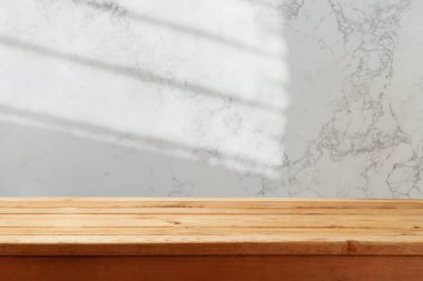 Mermer duvarın üzerine boş ahşap masa ve pencere arkasından gelen ışık ışınları. Model tasarımı için mutfak tezgahı