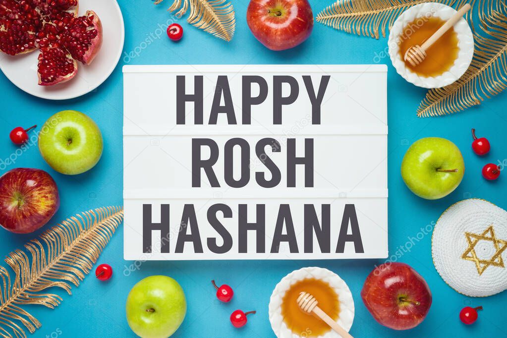 Jewish holiday Rosh Hashana concept with honey, apple and pomegranate over blue background