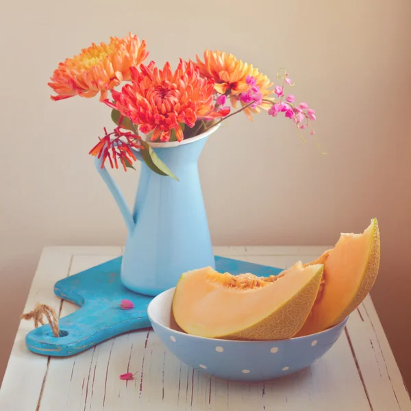 Melón y flores en mesa vintage. Céntrate en el melón. Efecto filtro retro — Foto de Stock