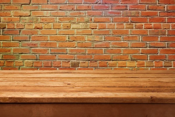 Prázdný dřevěný stůl a cihlová zeď — Stock fotografie