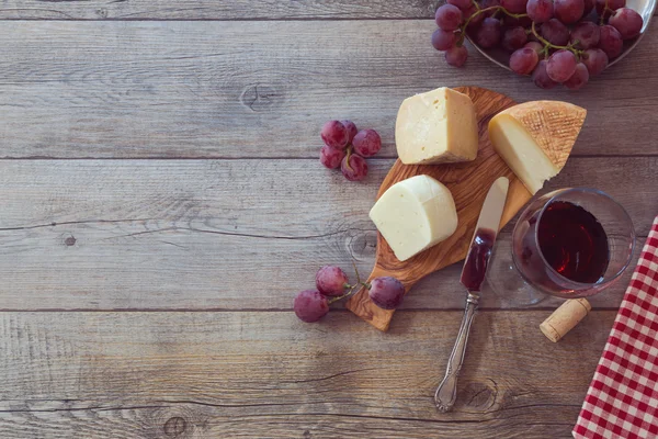 Κρασί, τυρί και σταφύλια στο ξύλινο τραπέζι — Φωτογραφία Αρχείου