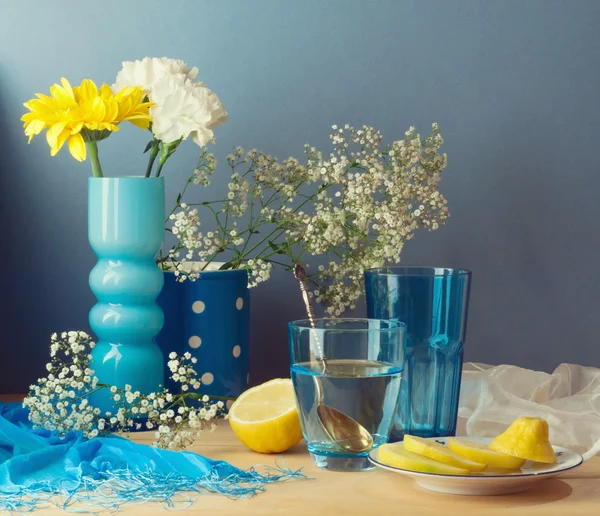 Stilleben med vatten, citron och blommor — Stockfoto