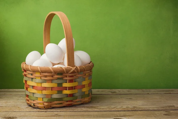 Eggs in basket on wooden table — Stock Photo, Image