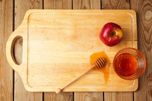 Manzanas y miel sobre tabla de madera —  Fotos de Stock